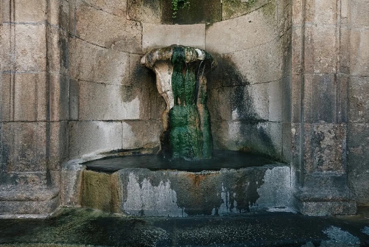 Caño de piedra de la fuente de As Burgas, con el agua caliente cayendo sobre la pila