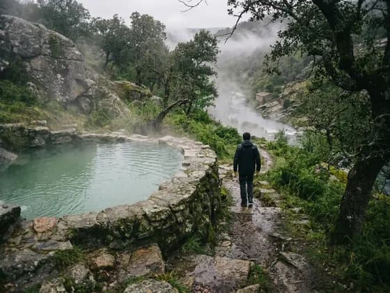 Sendero de piedra que baja hacia una poza y un río con vapor (imagen ilustrativa generada por IA)